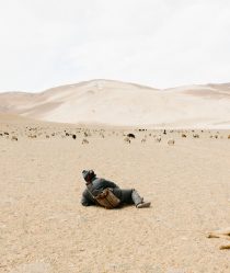 Young Kashmirin boy lies in a dessert looking at mountains