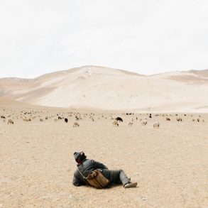 Young Kashmirin boy lies in a dessert looking at mountains