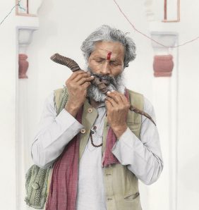 An old Indian man plays on a wooden flute