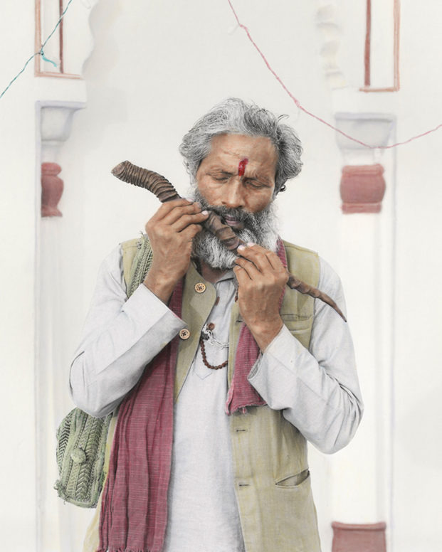 An old Indian man plays on a wooden flute