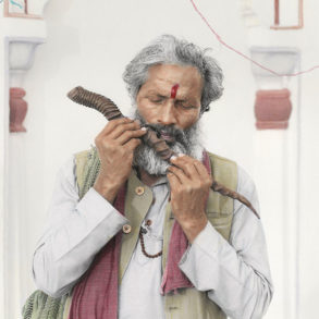 An old Indian man plays on a wooden flute