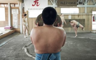 A young Japanese sumo carries a heavy weighted rock