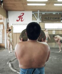 A young Japanese sumo carries a heavy weighted rock