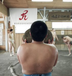 A young Japanese sumo carries a heavy weighted rock