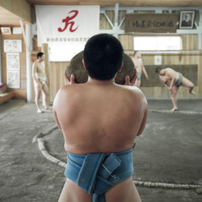 A young Japanese sumo carries a heavy weighted rock