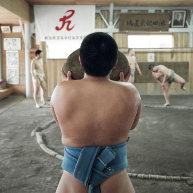A young Japanese sumo carries a heavy weighted rock