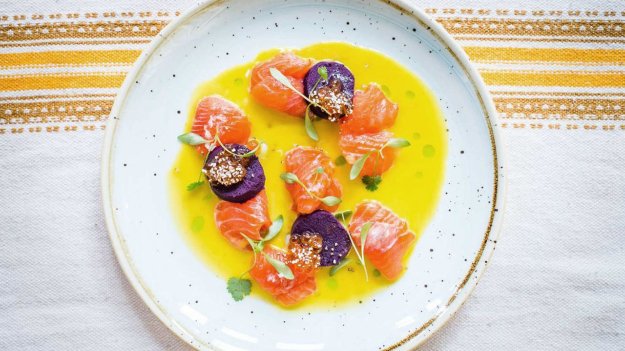 Trout and toradito ceviche in a bowl of tiger's milk dressed with sprigs of green