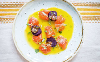 Trout and toradito ceviche in a bowl of tiger's milk dressed with sprigs of green