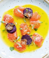 Trout and toradito ceviche in a bowl of tiger's milk dressed with sprigs of green