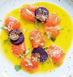 Trout and toradito ceviche in a bowl of tiger's milk dressed with sprigs of green