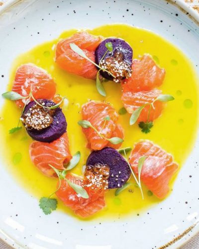 Trout and toradito ceviche in a bowl of tiger's milk dressed with sprigs of green