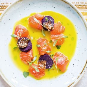 Trout and toradito ceviche in a bowl of tiger's milk dressed with sprigs of green
