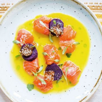 Trout and toradito ceviche in a bowl of tiger's milk dressed with sprigs of green